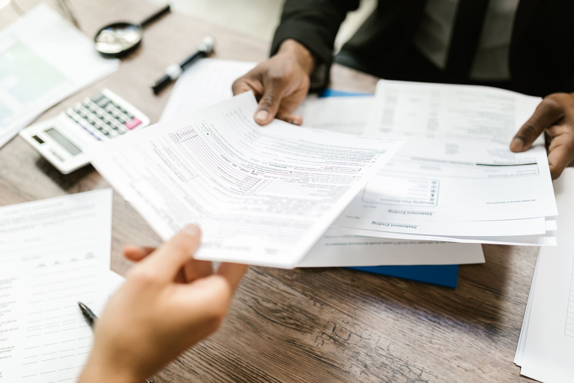 Hands exchanging paperwork across a desk