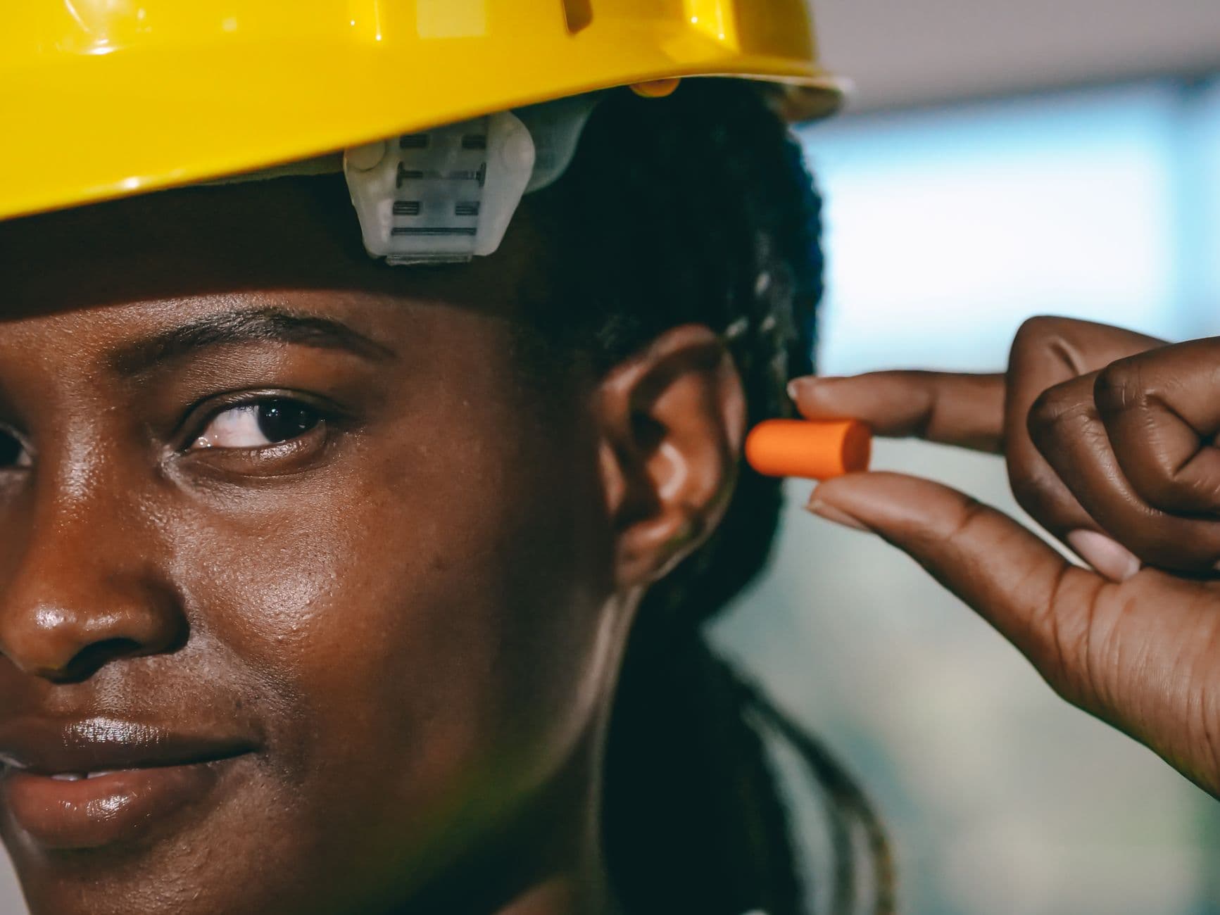 Construction worker fitting an earplug on a job site