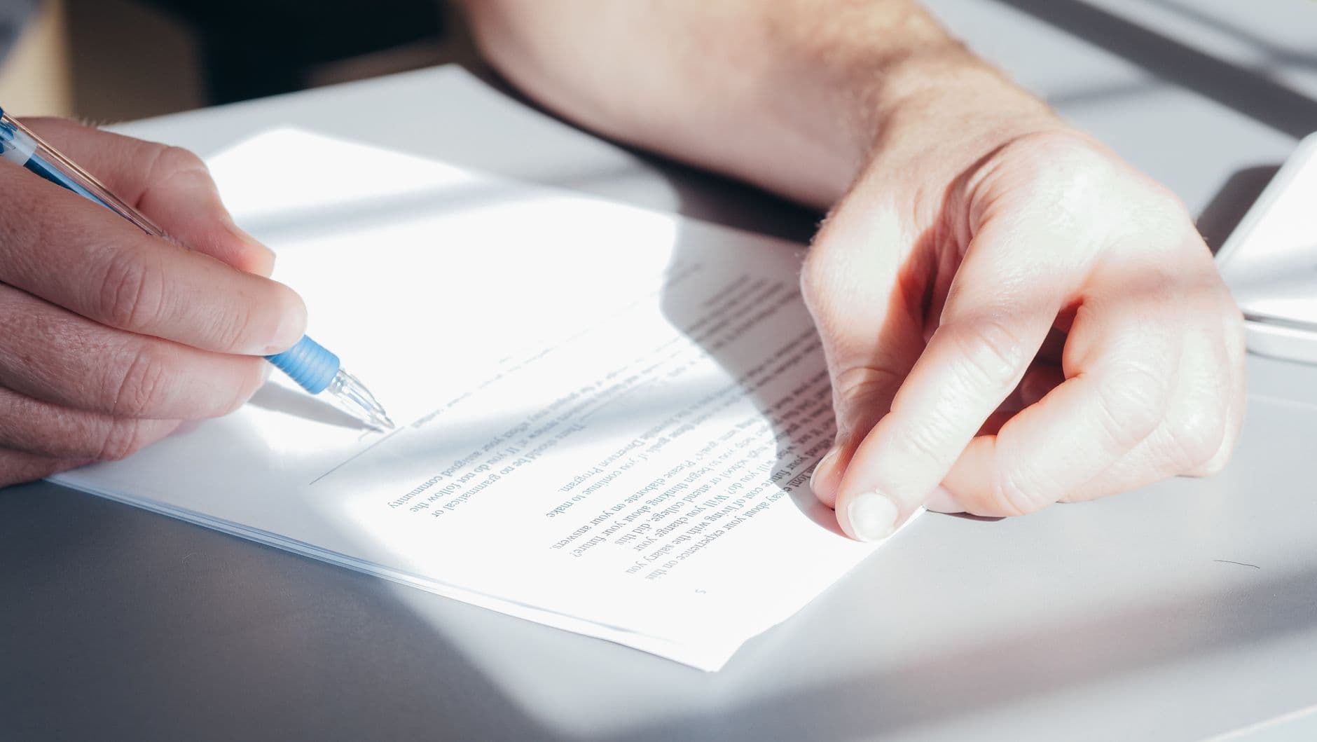 Hands signing a form with a pen