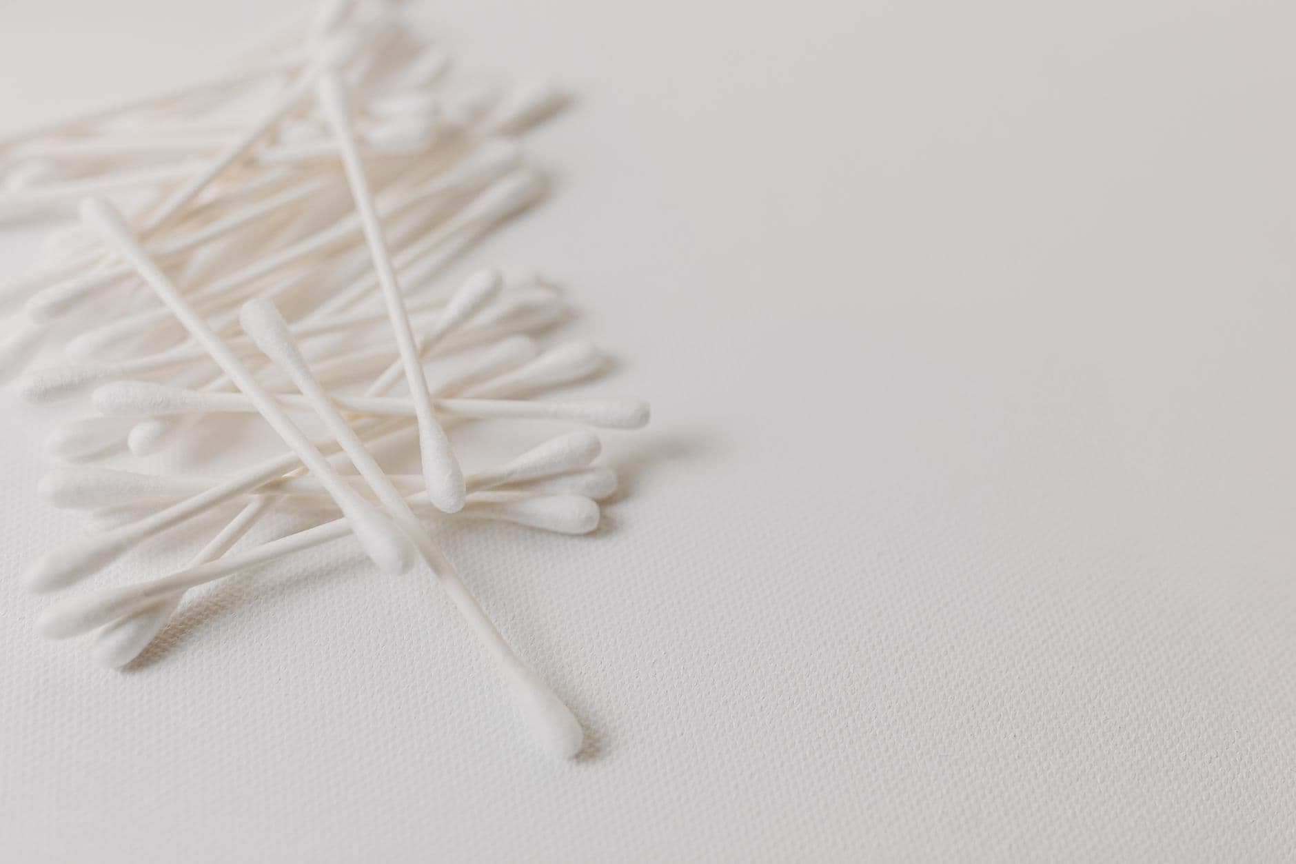 Cotton buds on a white surface, the kind that can push wax deeper into the ear