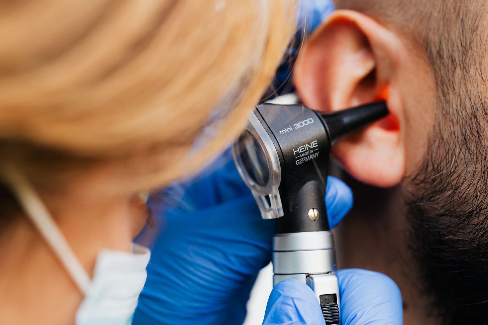 Clinician using an otoscope to look in an adult patient ear