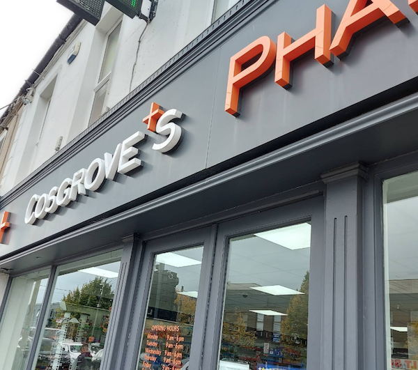 Cosgrove's Pharmacy storefront with orange and white signage. Hours visible on the door.